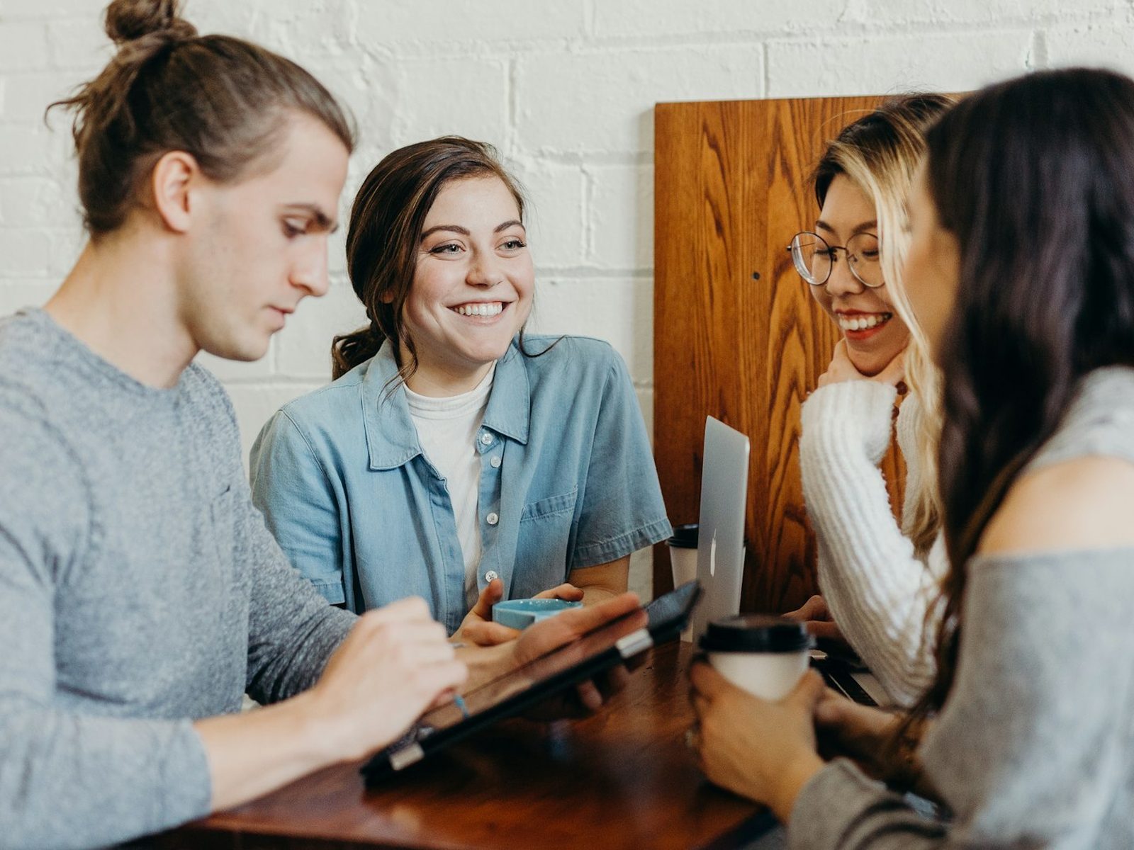 Four people talking and laughing around a cafe table