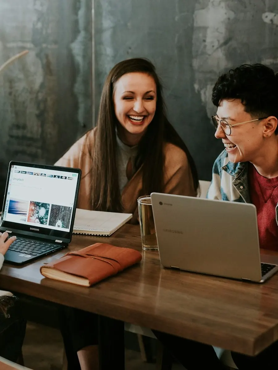 A young team laughing together around their laptops