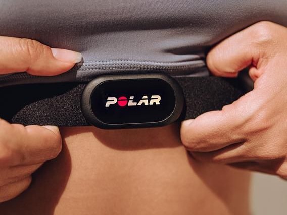 Hands fastening a Polar H10 chest strap under a shirt